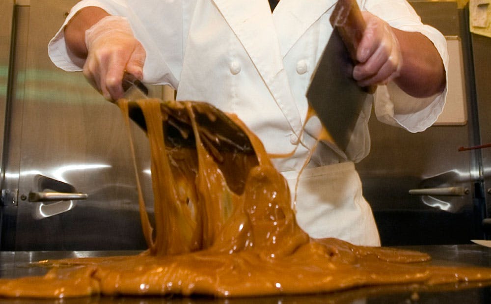 A candymaker uses special metal tools to mix caramel-colored toffee at Mouses' Chocolates in Ouray, Colorado.