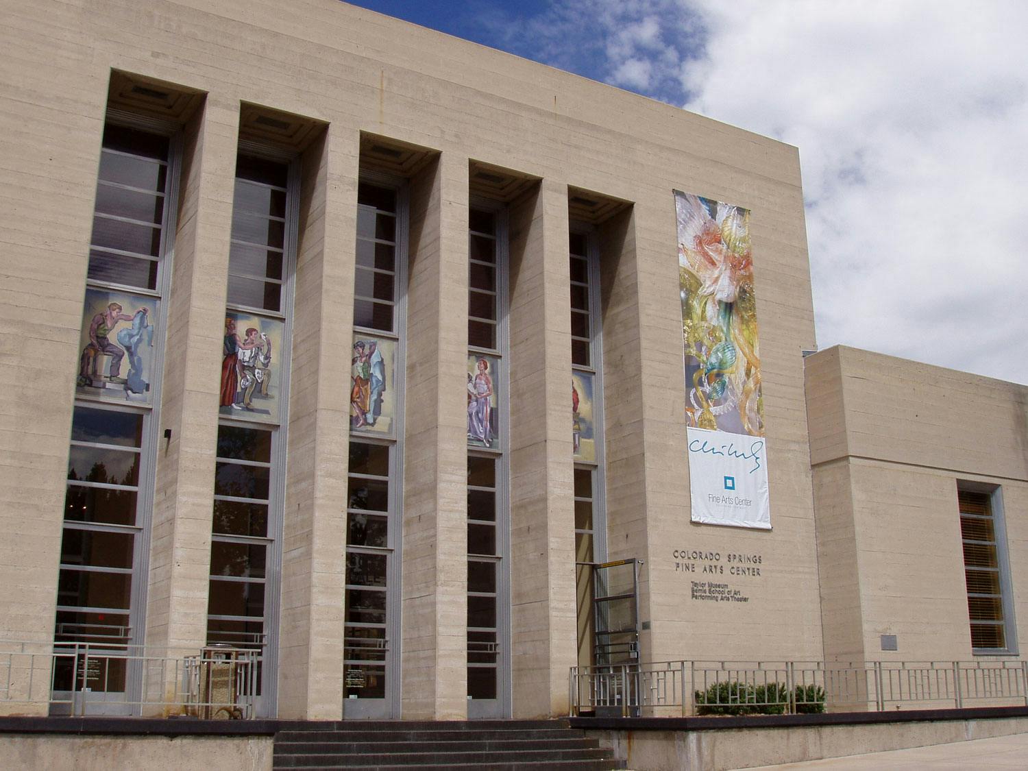 Artwork with human figures is featured between the concrete columns and windows of the Colorado Springs Fine Arts Center.