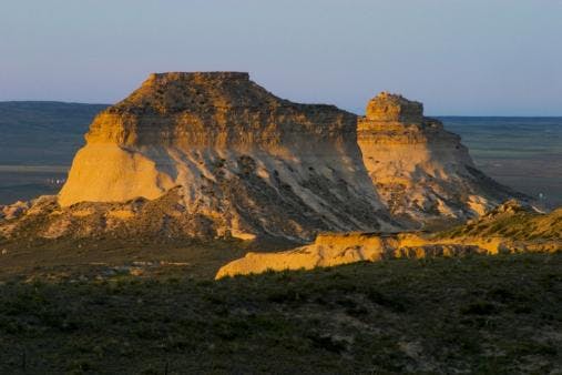 Two buttes rise up seemingly in the middle of nowhere, surrounded by flat prairie land