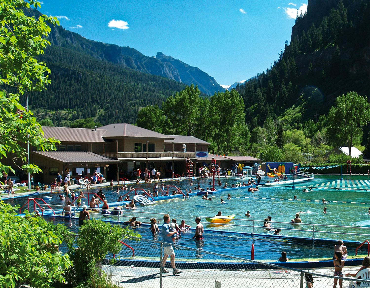 Groups of swimmers relax and play in the large pool areas of Ouray Hot Springs Pool.