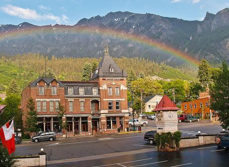 A full rainbow is seen arching over a Victorian-era brick building