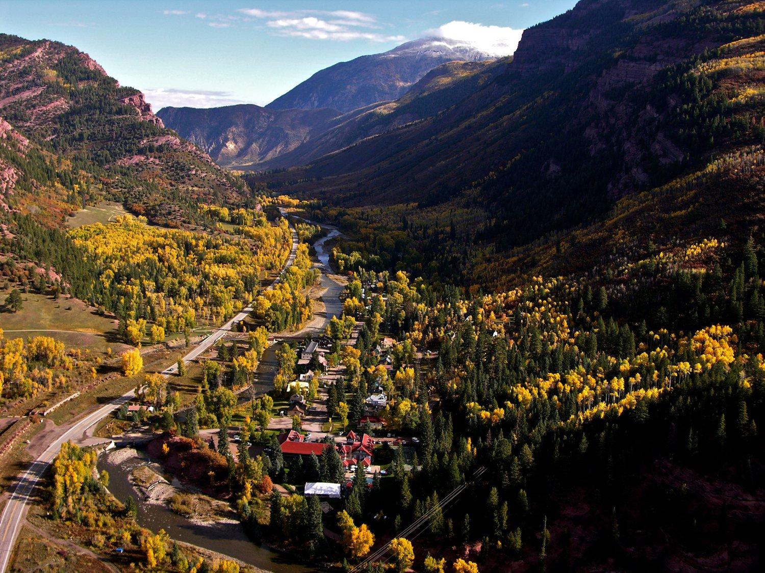 An aerial view of downtown Redstone in a valley of mountains on both sides. There are golden aspens and evergreen trees dotting the landscape.