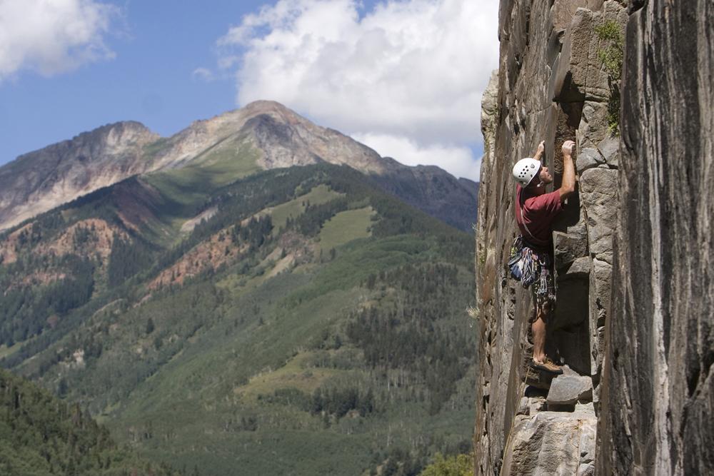 A person in climbing equipment scales a rock wall in southwest Colorado's San Juan Mountains