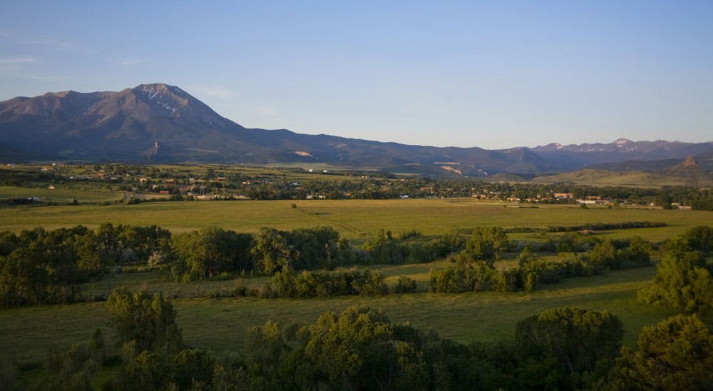 A lush green valley floor with a gray peak rising in the distance