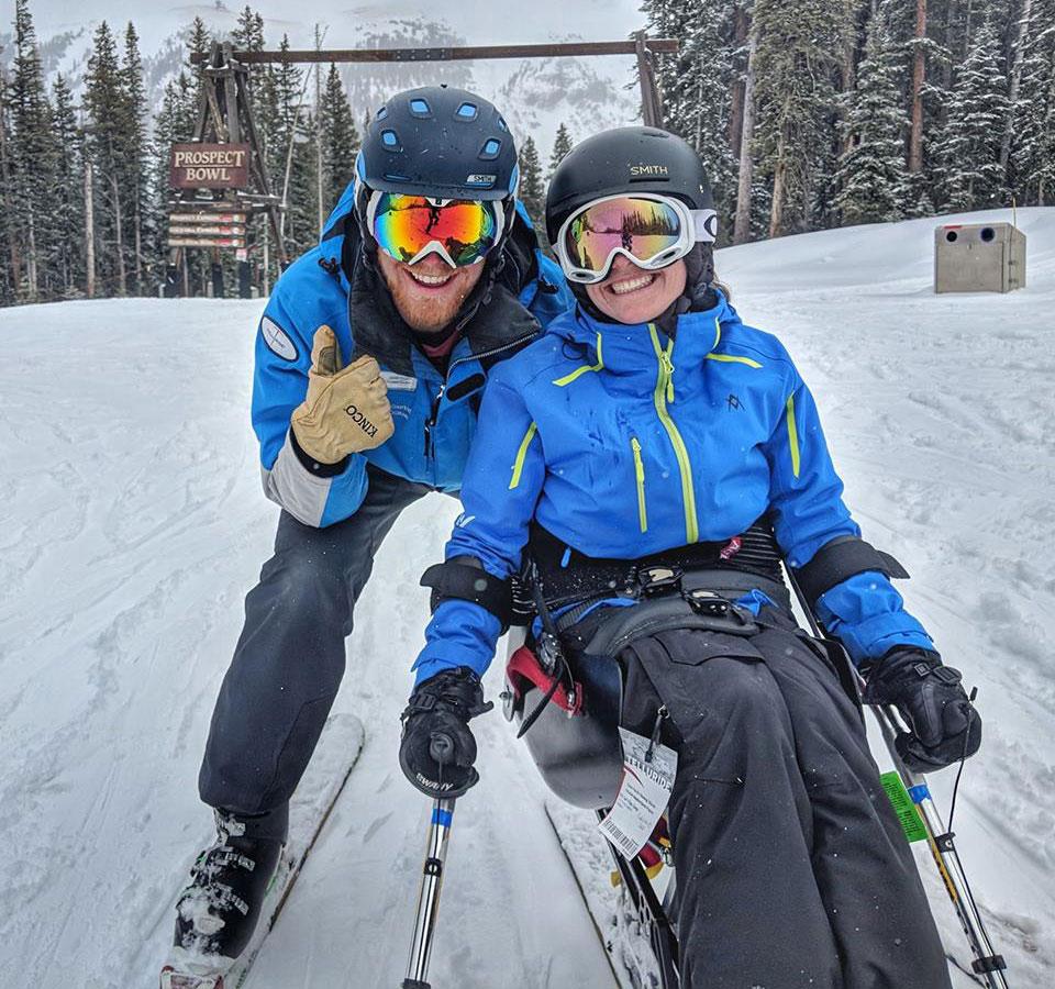 A ski instructor and a student learning to use an adaptive ski chair smile and pose for a photo in Telluride, Colorado.