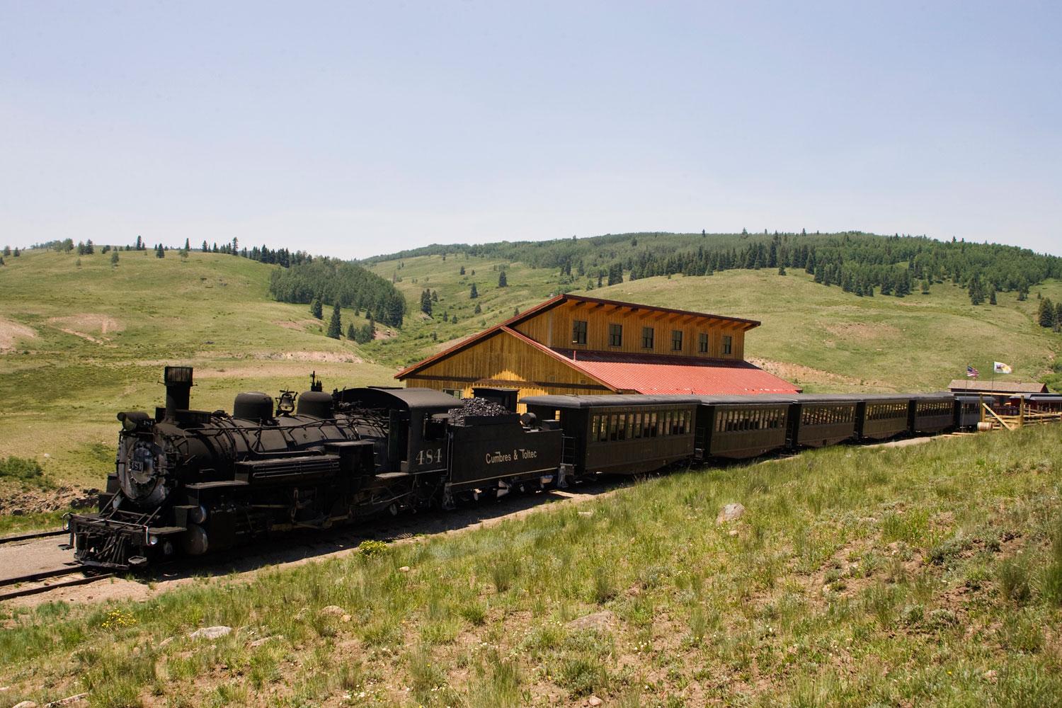 A train leaves the station surrounded by mountains