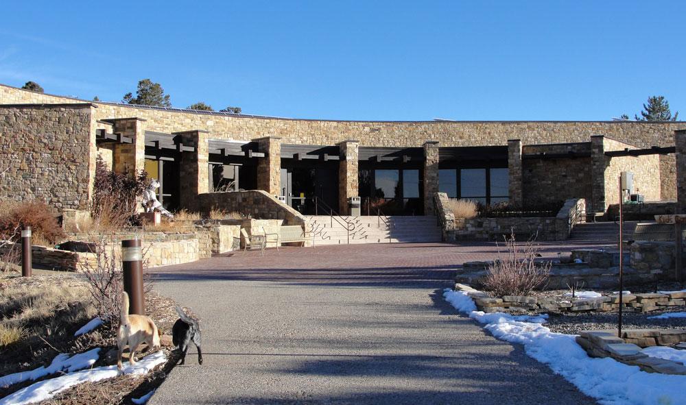 A sidewalk leads up to a curved stone building with large picture windows