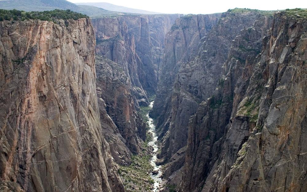 At the bottom of the deep Black Canyon of the Gunnison National Park, a rushing river pushes its way along the valley floor.