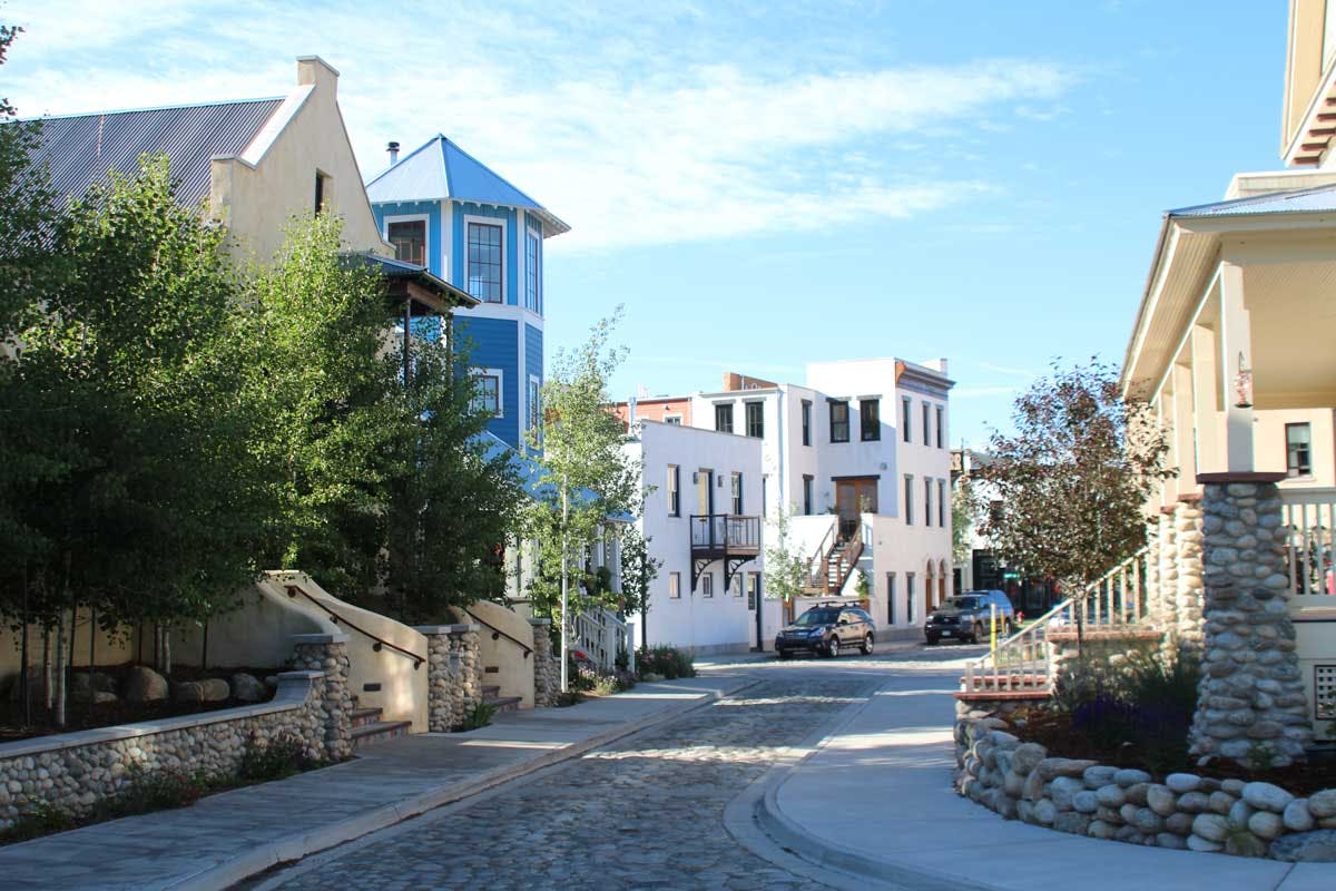 A stone street in Buena Vista in the summer with houses lining both sides. There's a blue sky with a whisp of a cloud.