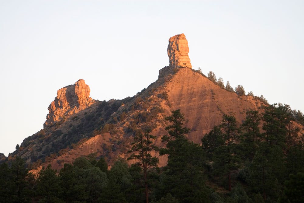 The two spires of Chimney Rock (that look like chimneys!) glow in the golden light of sunset