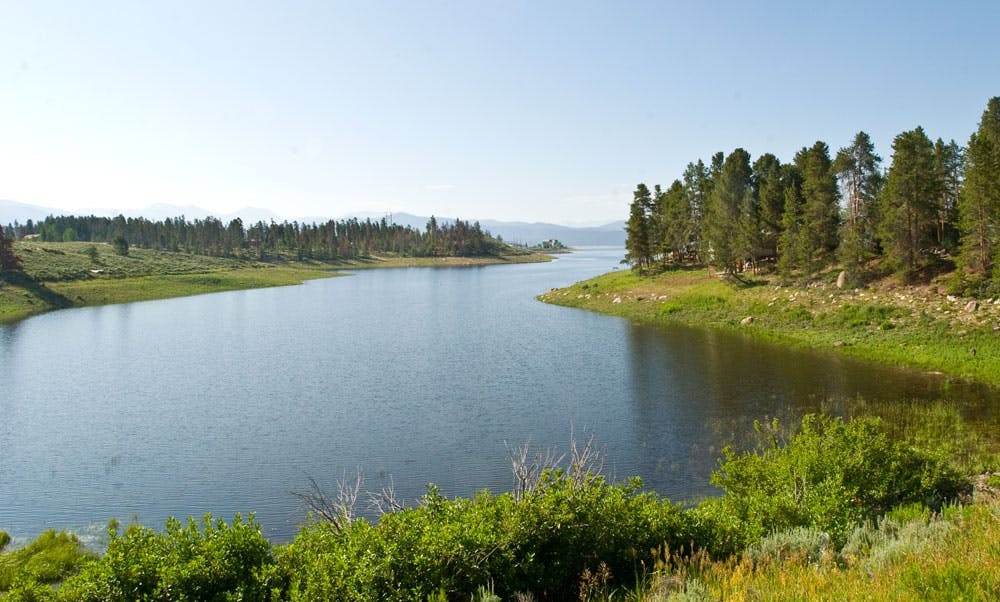 A slow-moving wide river winds its way through a green-forested landscape