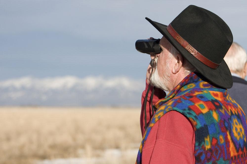 A man with binoculars looks for birds