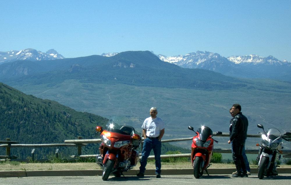 Motorcycle riders stop along the road to enjoy mountain views