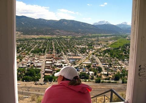 A woman looks out onto Salida along the Collegiate Peaks scenic byway; the town and mountains are laid out in front of her in a panoramic view.