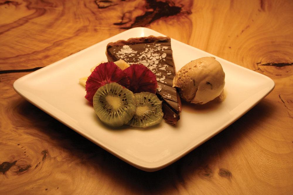 A slice of chocolate pie is topped with large flecks of salt and accompanied by sliced of kiwi and a scoop of caramel ice cream at Salt Bistro in Boulder, Colorado.