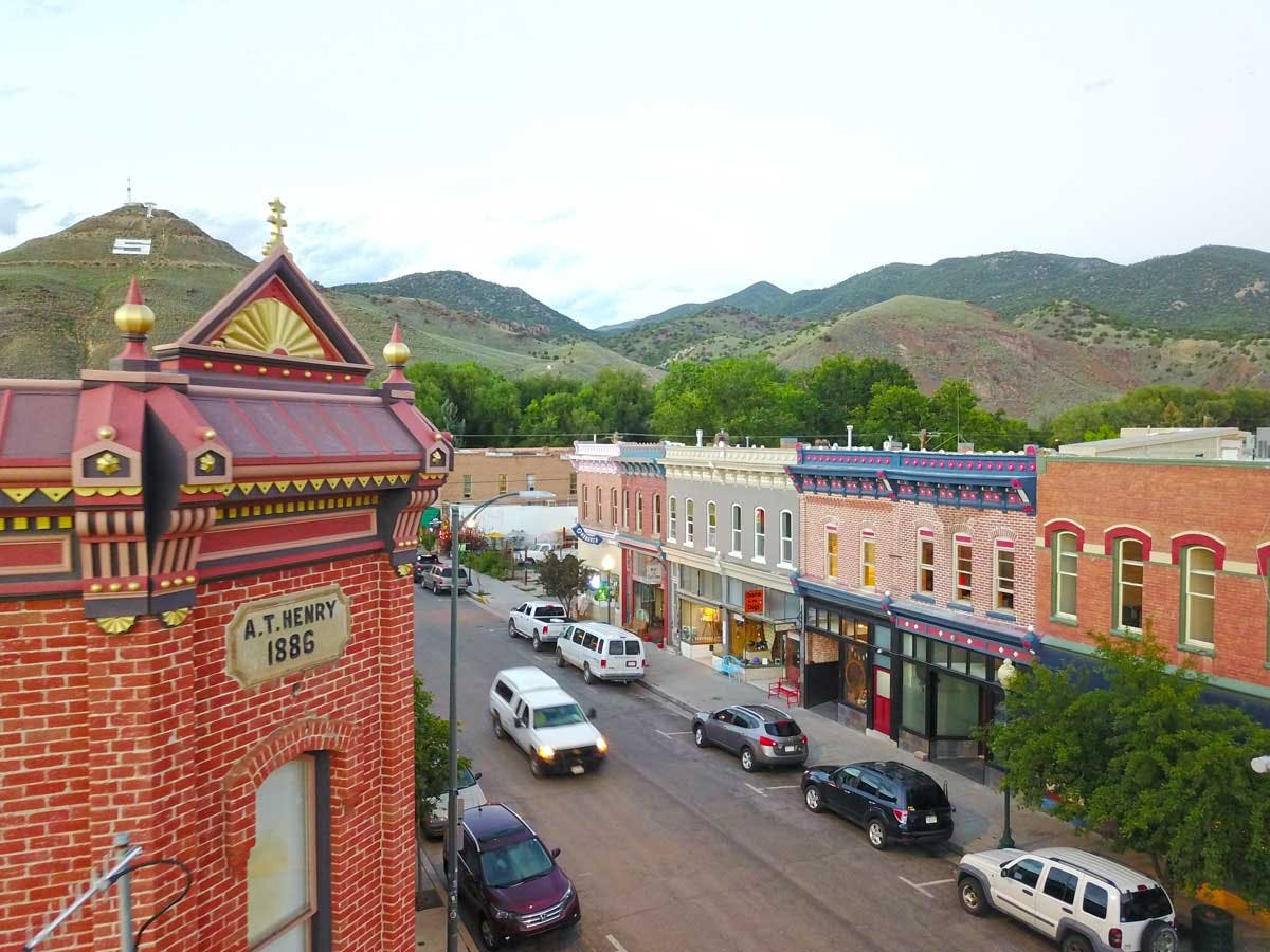 Victorian-era architecture in historic downtown Salida. In the distance green hills roll into a white sky.