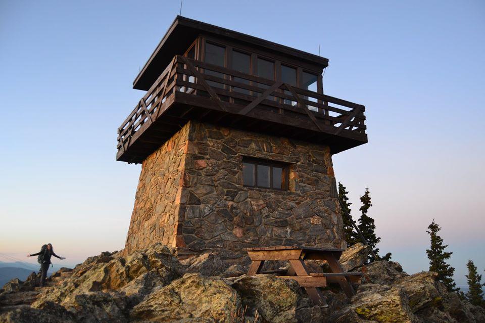 Mestaa’Ėhehe Mountain Fire Lookout perched on a mountain top and surrounded by small fir trees.