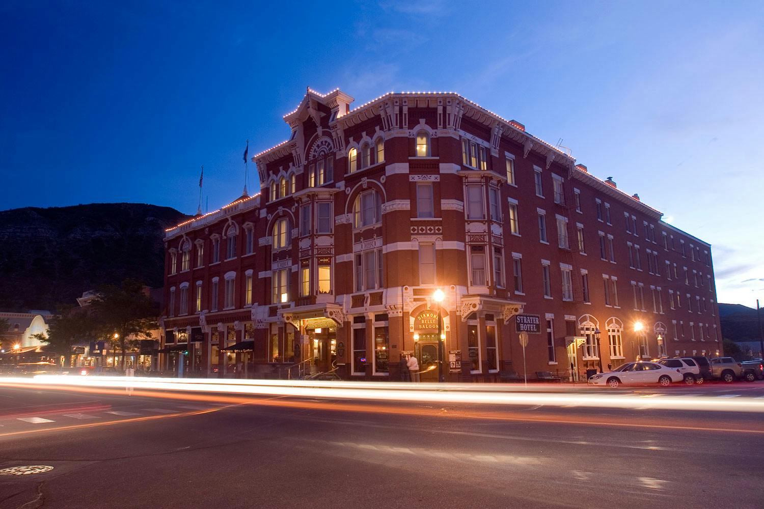 Lights line the roof of the brick and marble Historic Strater Hotel in Durango, Colorado. The light glow bright as the evening sky darkens.