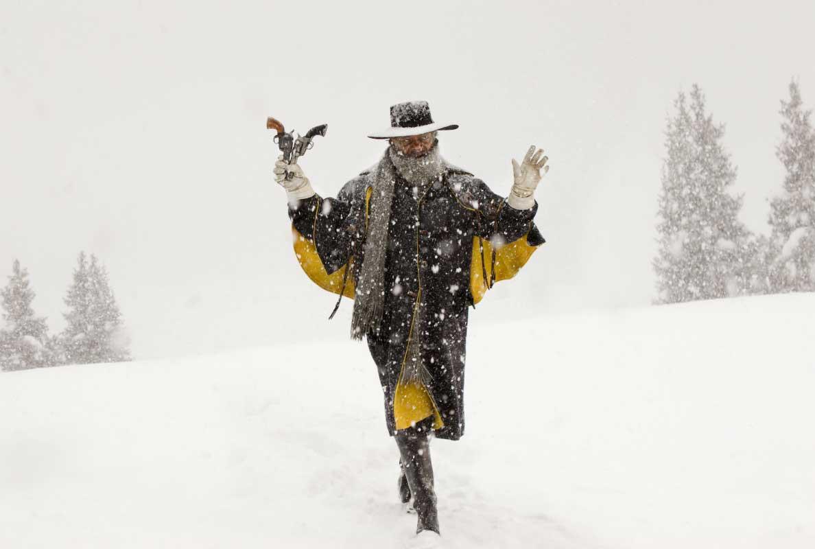 Joe Gage holds two pistols in the air as he walks through a snowy meadow during a scene from 'The Hateful Eight' near Telluride