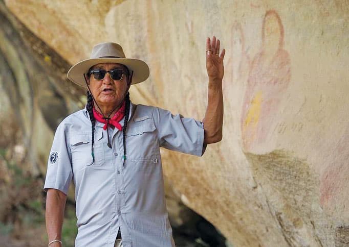 Tour guide gestures to petroglyphs at Ute Mountain Ute Tribal Park in Towaoc