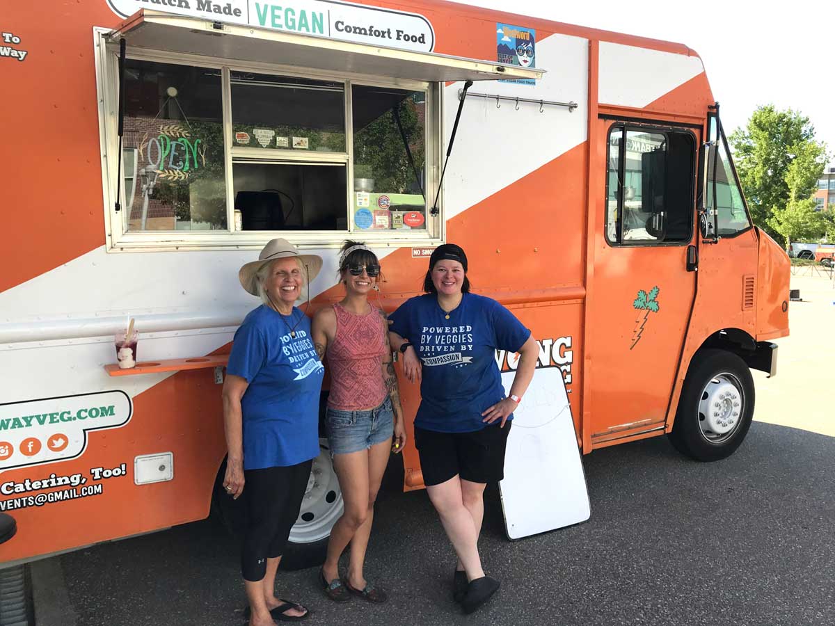 Three people stand in front of the bright-orange-and-white Wong Way Veg food truck in Denver