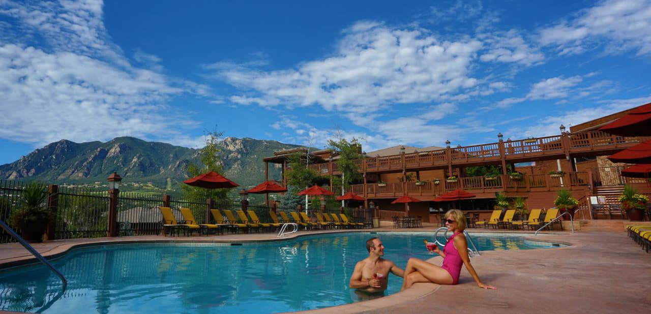 A couple sits poolside at a mountain resort