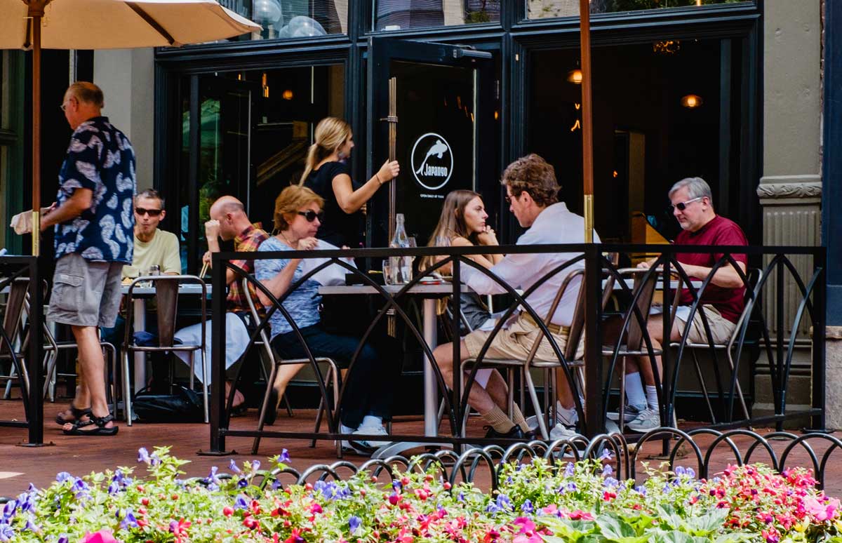 Diners sit at tables under white umbrellas
