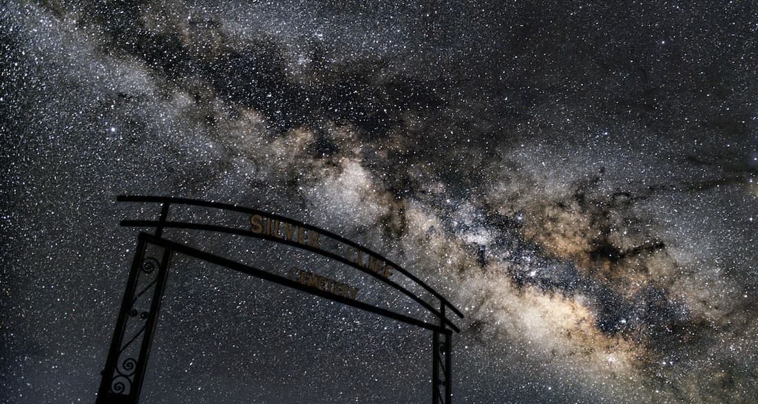 Thousands of stars at night behind a gate to the Silver Cliff cemetery