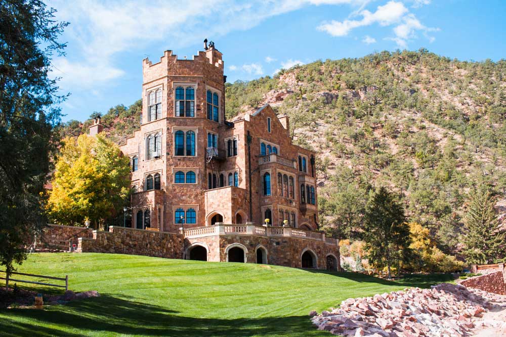 A red brick castle as seen from a manicured green lawn