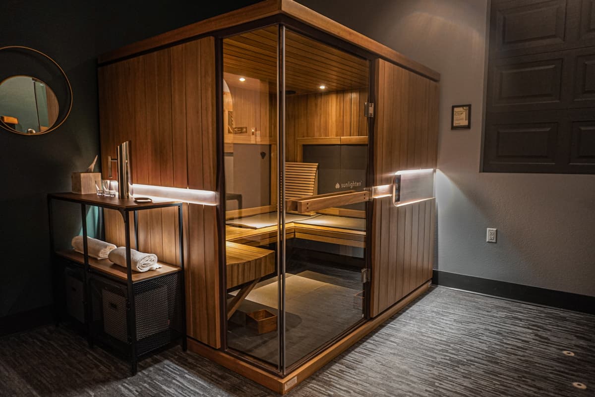 The sauna at Oakwell Beer Spa, illuminated dimly by warm lights. Surrounding the infrared sauna are towels and essential oils.