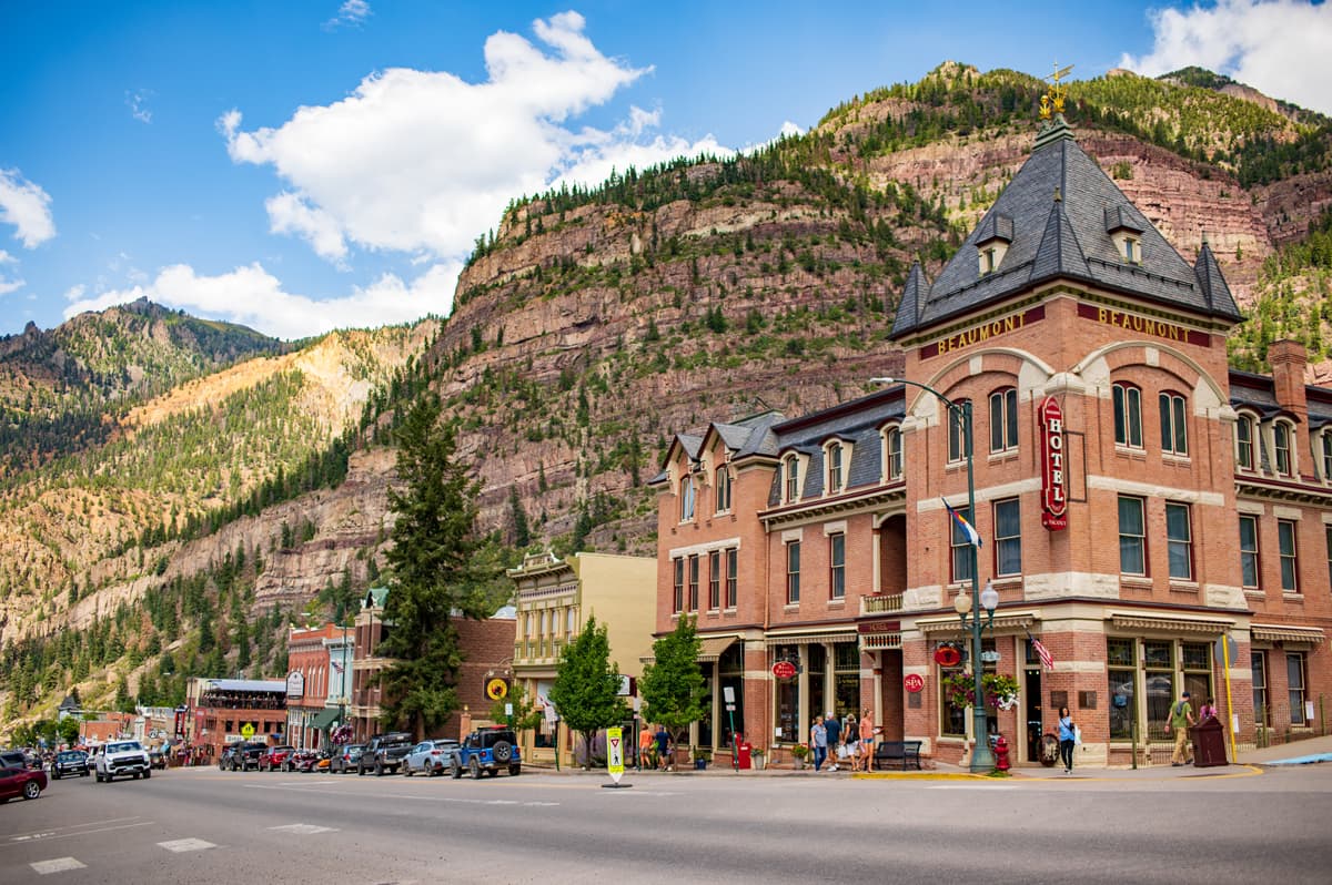 A Victorian hotel with a canyon wall rising behind it in Ouray Colorado