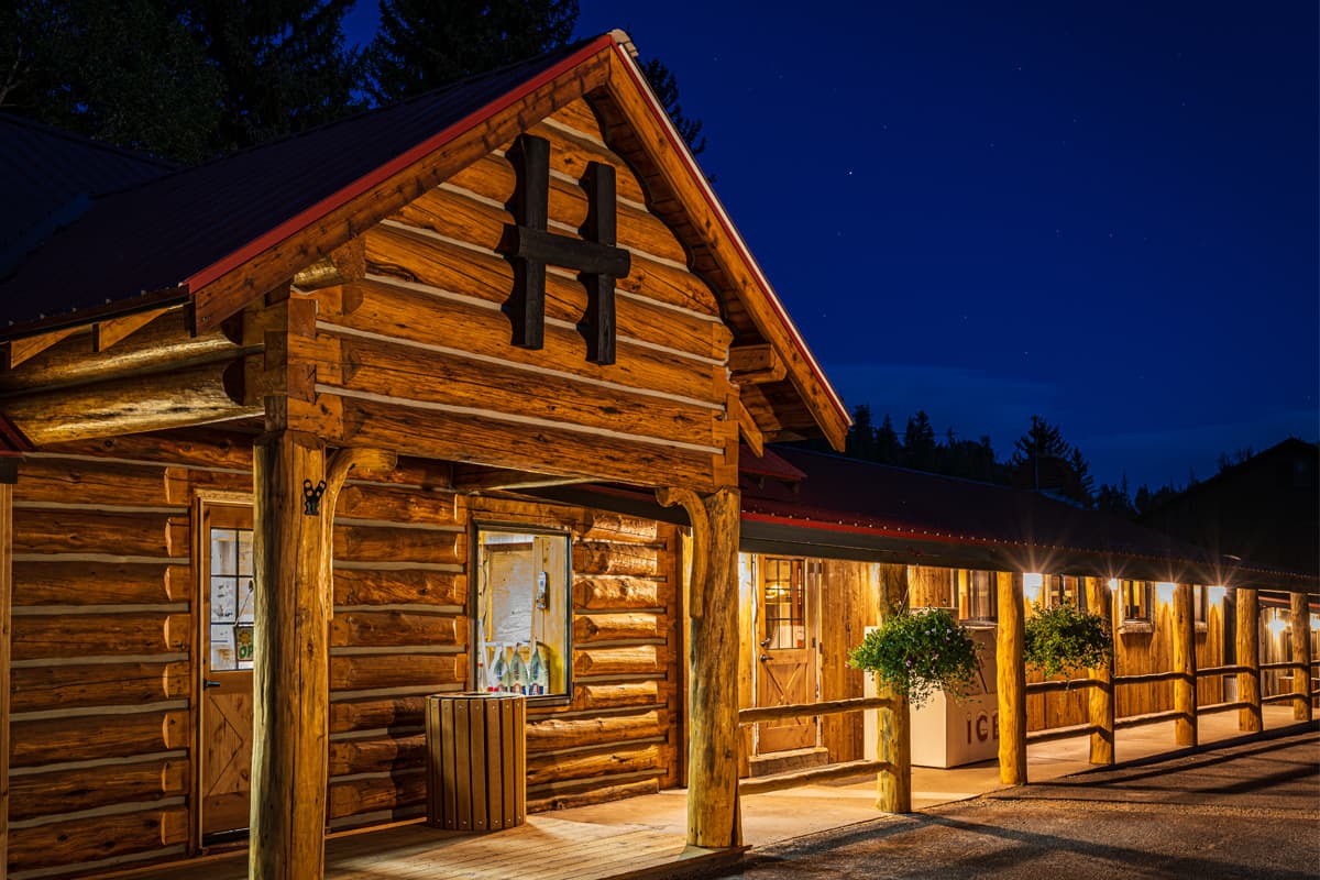 Th e porch at Harmels on the Taylor main lodge is lit up with lights. In the background, there is a dark sky glittering with stars.