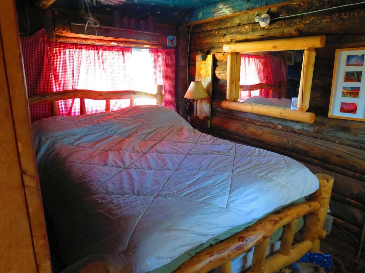 The bedroom at Colorado Cabin Escape fits two people. The bed frame is made from logs.