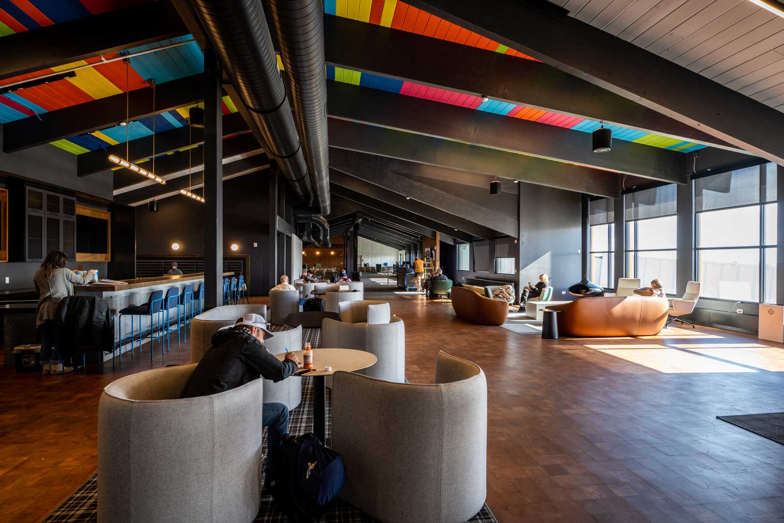 People sit in the Gunnison-Crested Butte airport lounge; sun streams in from a window