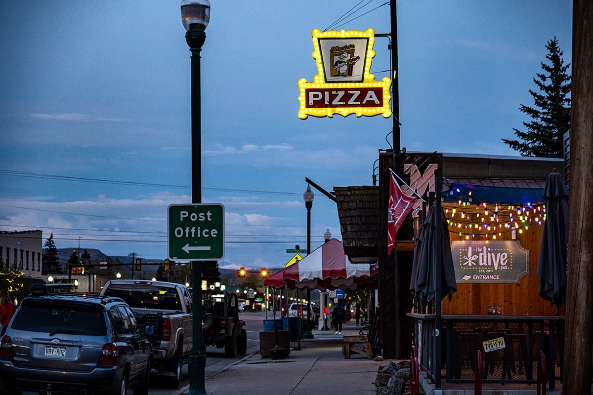 Evening street scene with a neon sign above a restaurant that reads "Pizza"