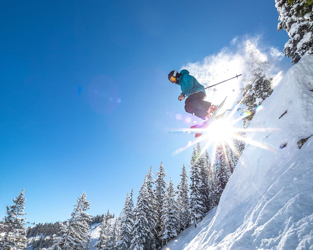 Skier in the air going over a ski jump on a steep mountain