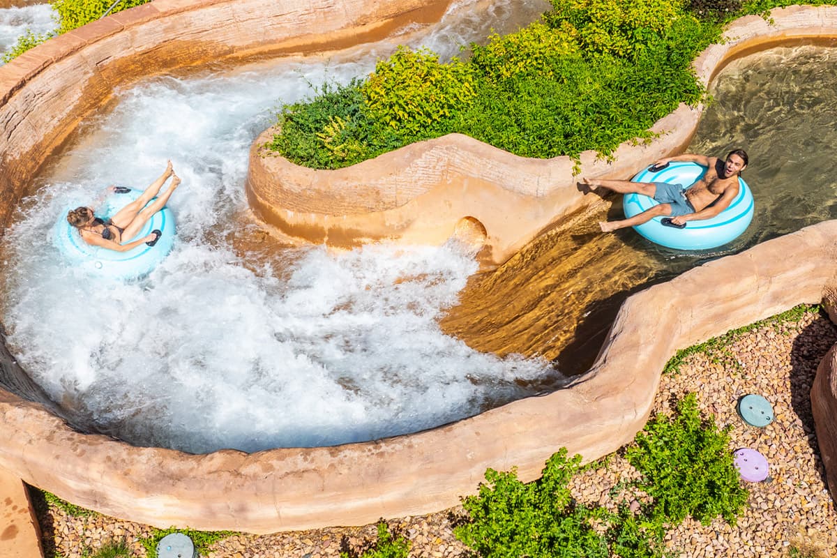 Two people float through the sudden drops and speedy rapids of the Glenwood Hot Spring Resort's Shoshone Chutes in blue innertubes.