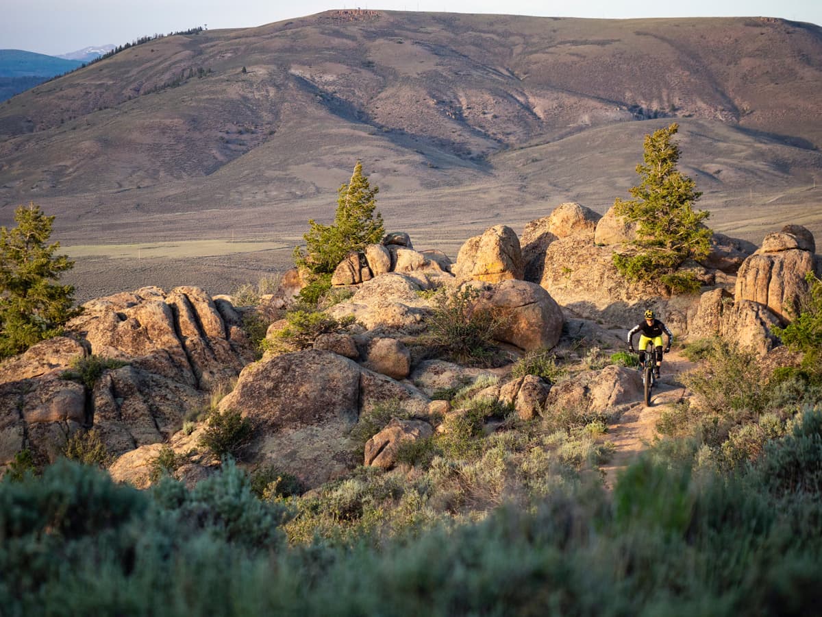 A mountain biker climbs over rock formations in Hartman Rocks Recreation Area in Gunnison Coloraod