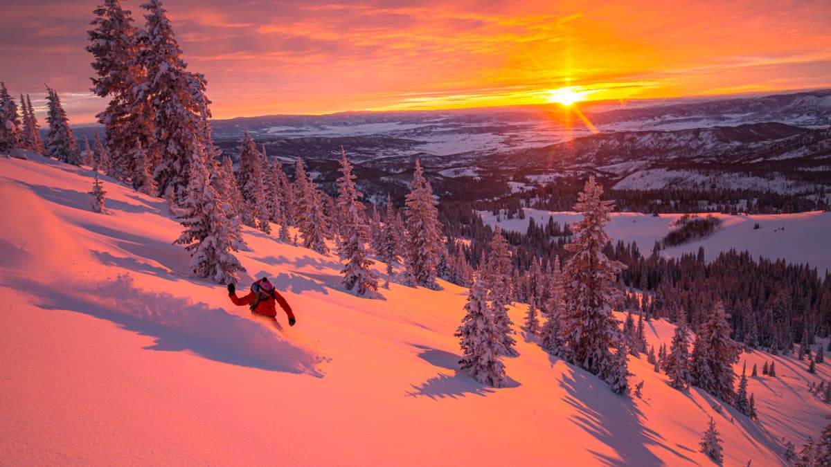 Snowboarding at sunset with golden-hour dues painting the sky in Steamboat Springs, Colorado.