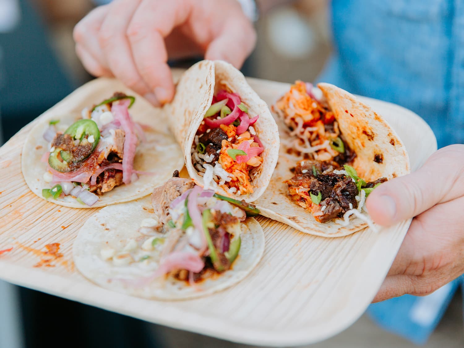 A plate of carnitas street tacos garnished with pickled red onion, scallions and jalepeno in Aurora, Colorado.