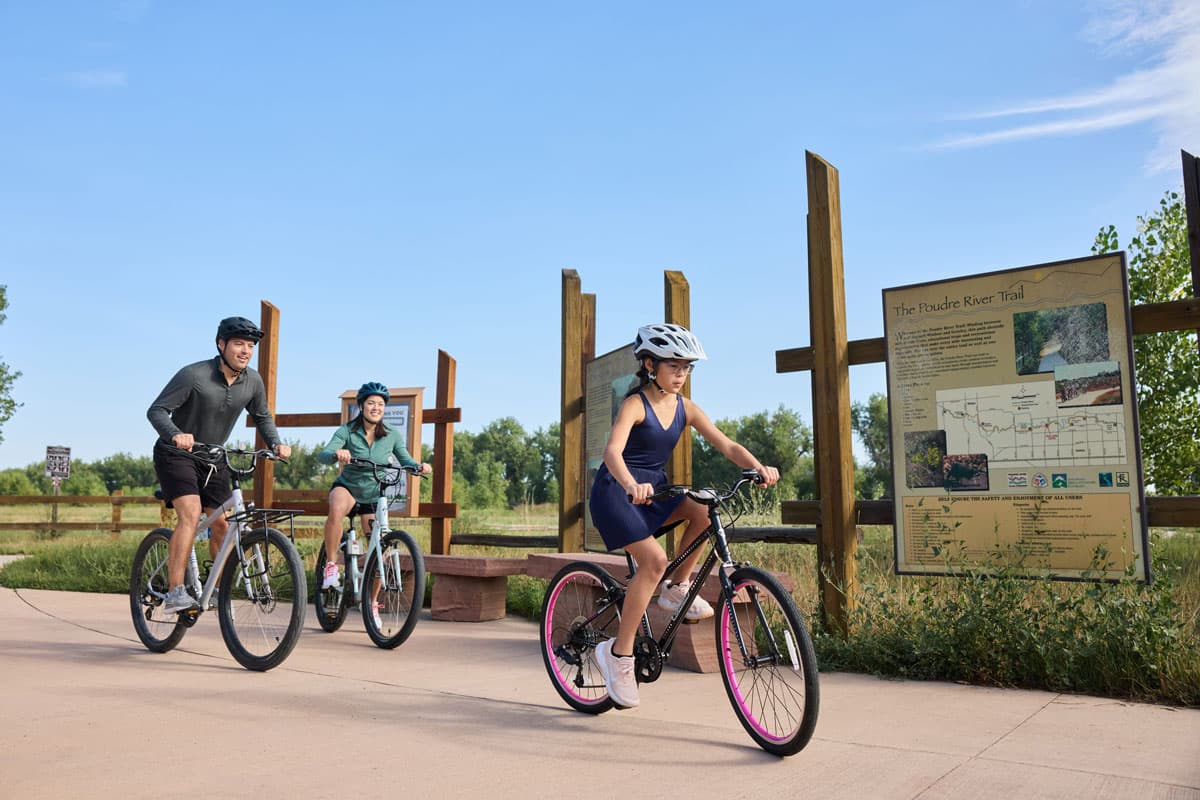 Family biking the Poudre River Trail on a warm day in Greeley, Colorado.