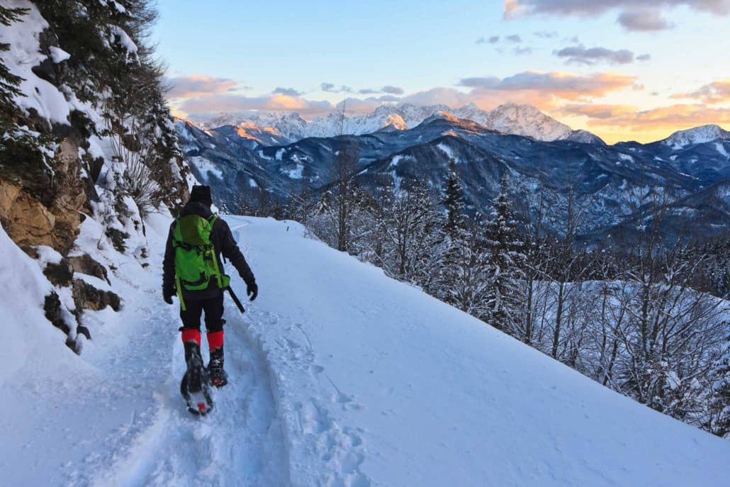 A person snowshoes along a ridge in Colorado as mountains with lavender clouds rise in the background on a Colorado Adventure Guides Tour.