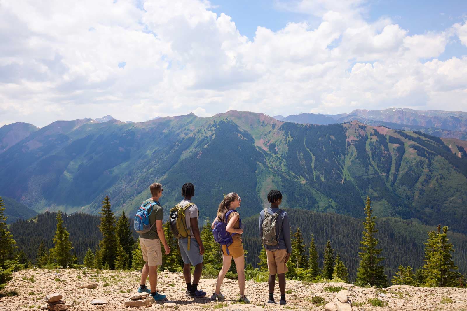 Four teens look out onto a mountain view from a hike
