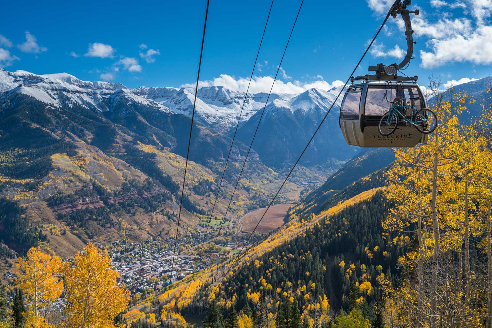The gondola at Telluride Mountain Village passes through mountain terrain and fall's yellow leaves