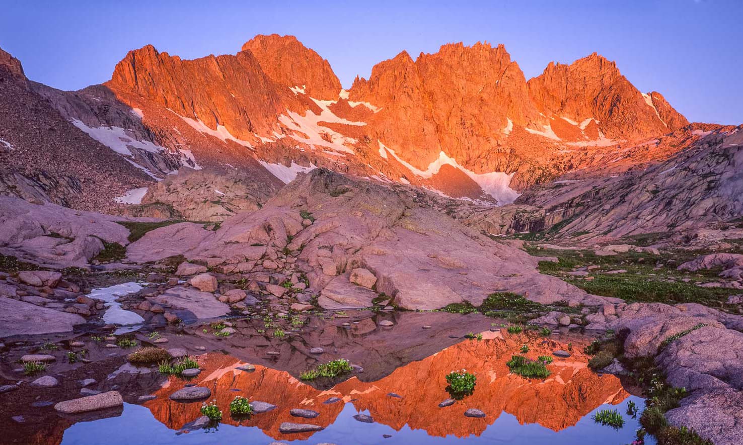 Sun rises on a jagged peak reflected in a Colorado lake