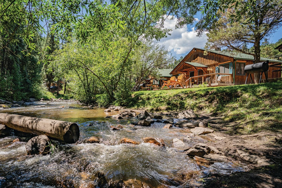 Bear Creek Cabins nestled in the woods surrounded by trees and the river.