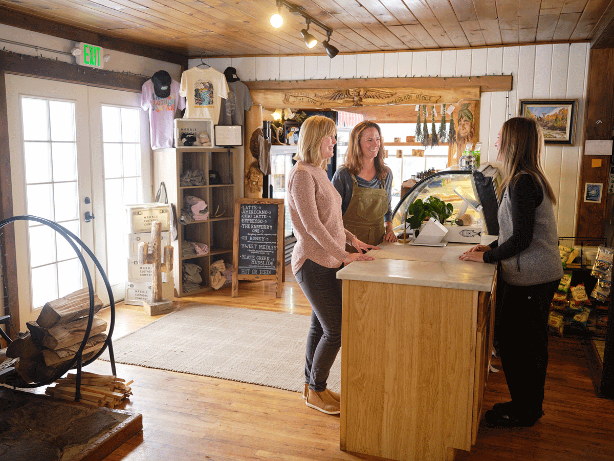 Customers ordering at the counter of Raspberry Ridge Cafe with a worker smiling at them.