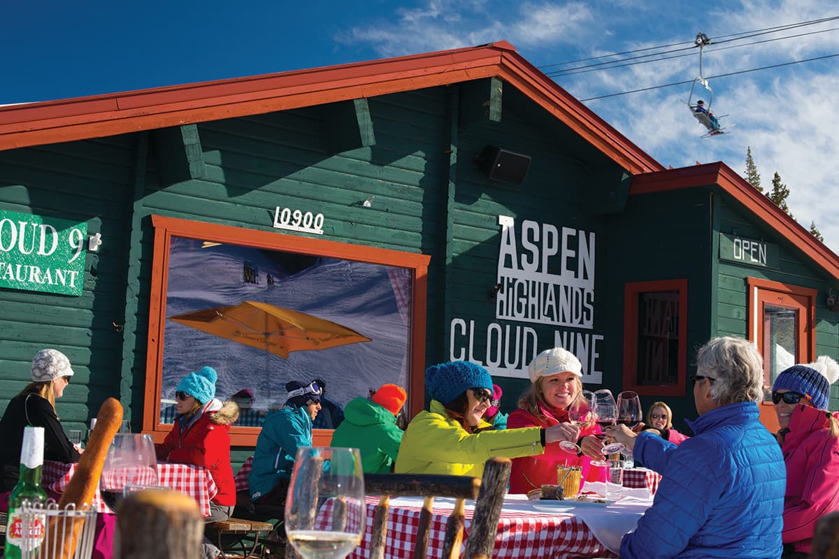 Diners sit outside at tables with checkered tablecloths at Aspen Highlands Cloud Nine in Aspen, Colorado.