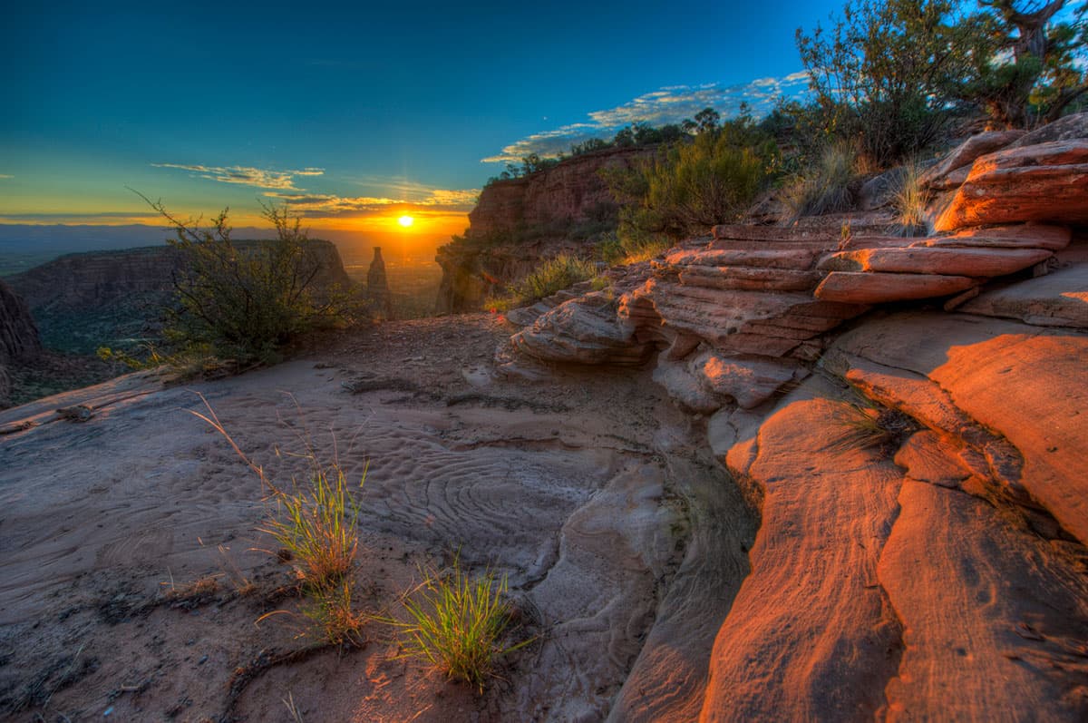 The sun rises and has just started to cast its rays on the red-rock outcroppings of the monument