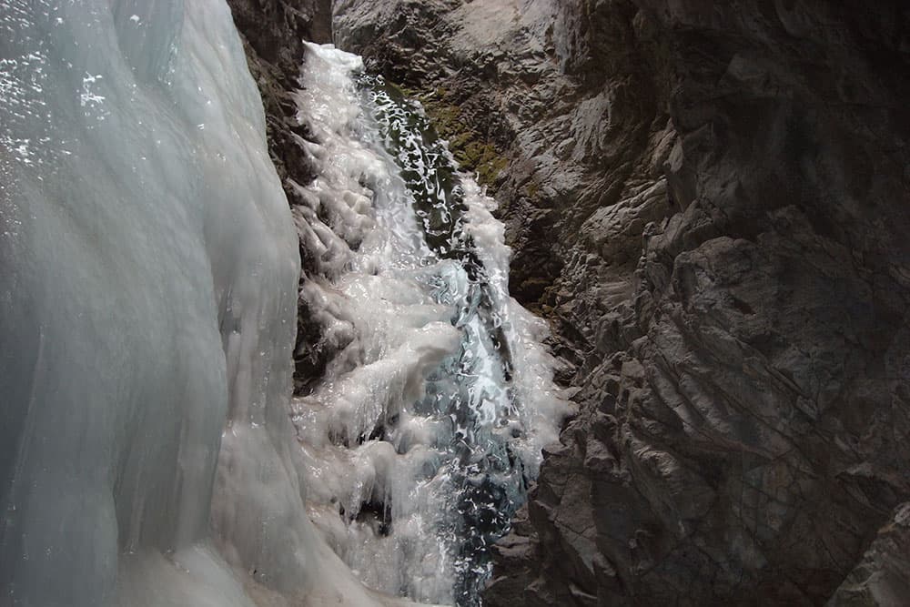 Water rushes down Zapata Falls, one side of the rock is covered in ice